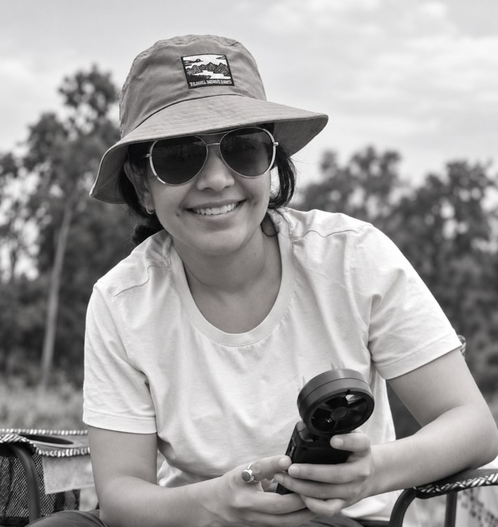 Zainab Khan outdoors during fieldwork, holding an instrument